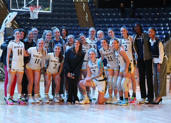 High school student singer stands with the Quinnipiac women's basketball team.