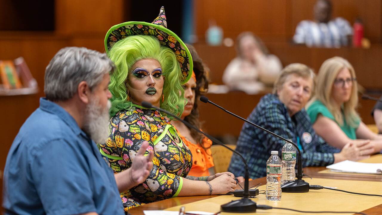 A drag queen listening intently to other panel members.