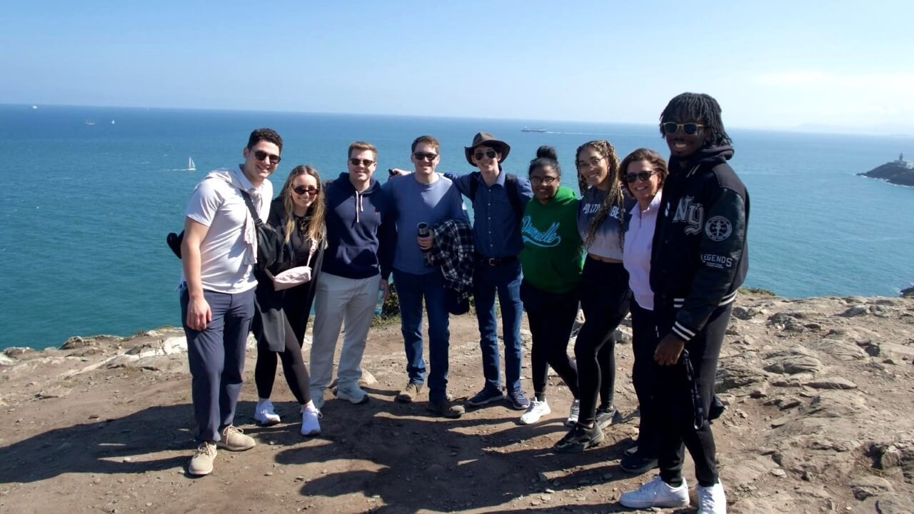 Group of students and a professor posing for a photo with a view of the ocean