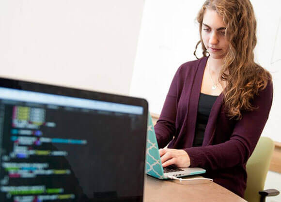 A student types at a laptop at her desk.