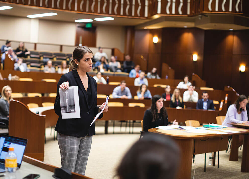 A law student holds up a piece of paper as evidence to the mock jury during a mock trial in the courtroom