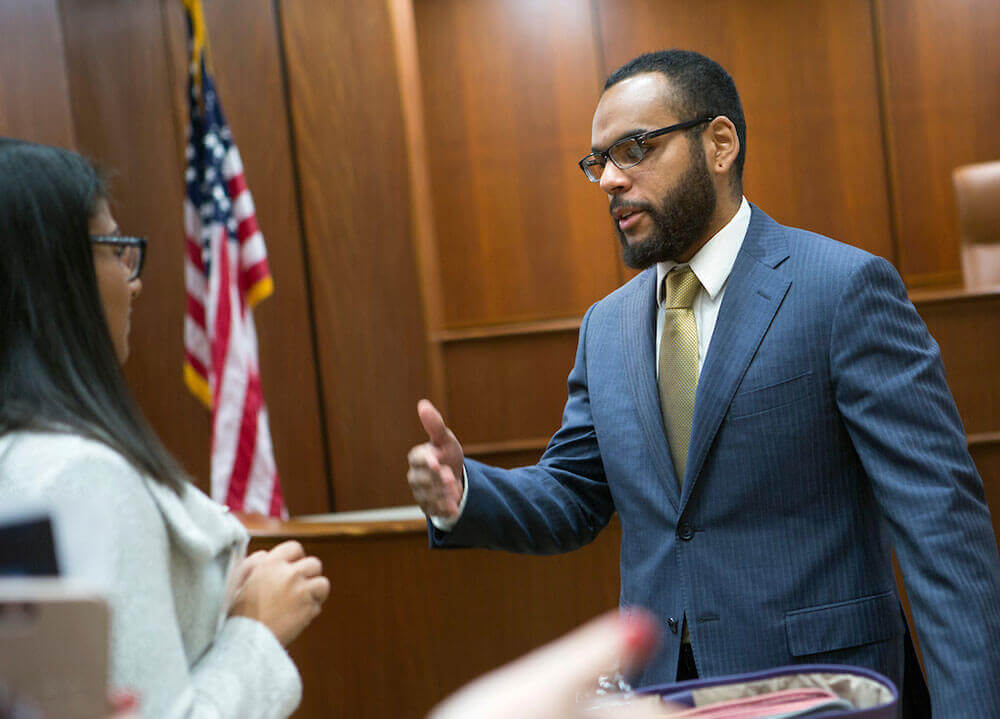 A law student wearing a blue pinstripe suit speaks with an attorney following her panel lecture in the ceremonial courtroom